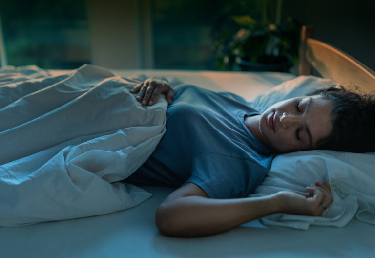 Young pretty woman sleeping in bed in night with street light coming from windows