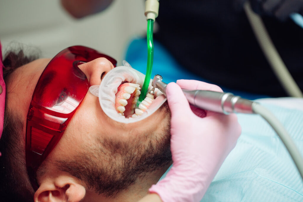 Professional teeth cleaning. Dentist cleans the teeth of a male patient