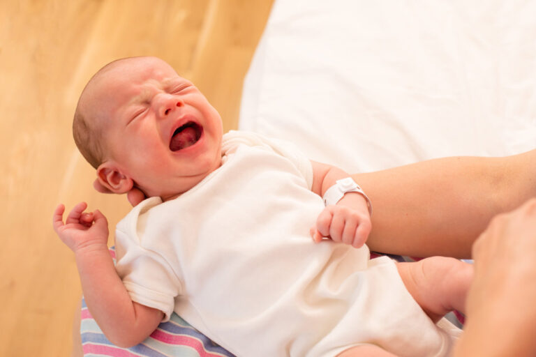Mom holds her screaming baby in her arms