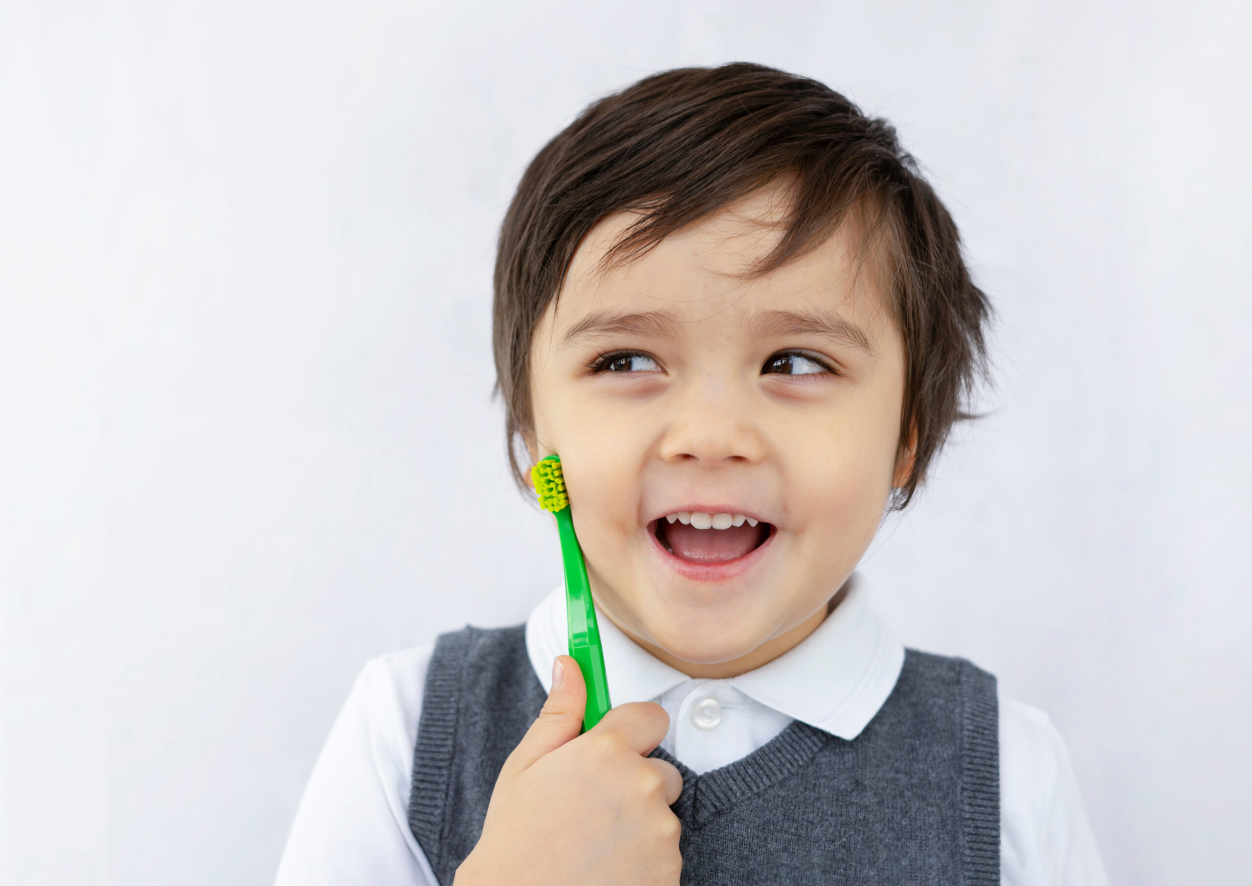Smiling child in school uniform holding a toothbrush, learning about dental hygiene
